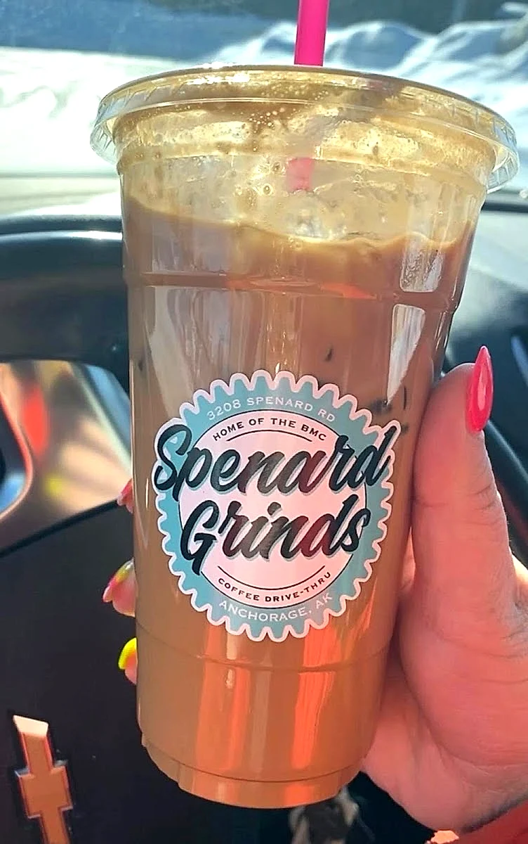 An iced Spenard Grinds coffee in a branded cup
